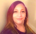 Woman with purple hair and hoop earrings against a neutral background